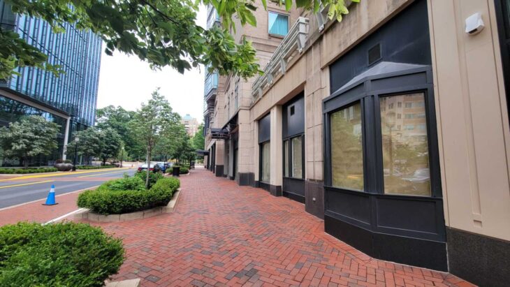 A store with a stone exterior and a bay window, and the sidewalk outside.