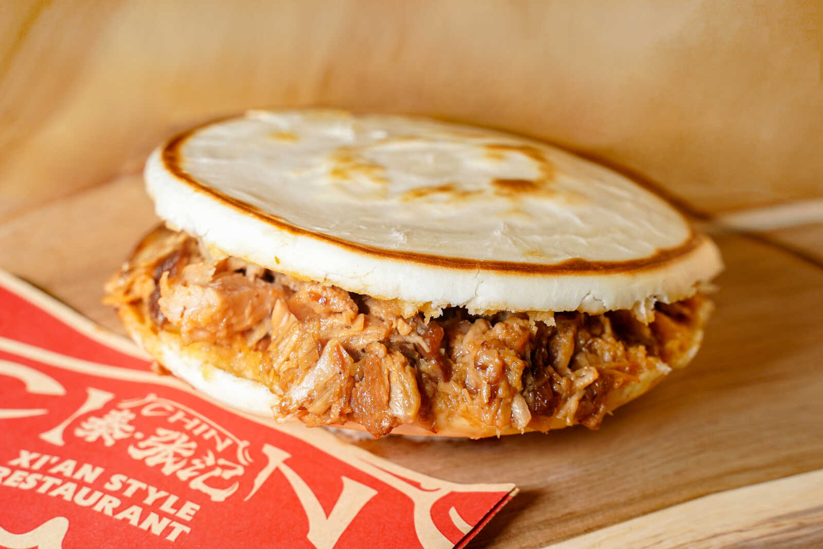 Pulled pork sandwich with a soft white bun on a wooden surface.