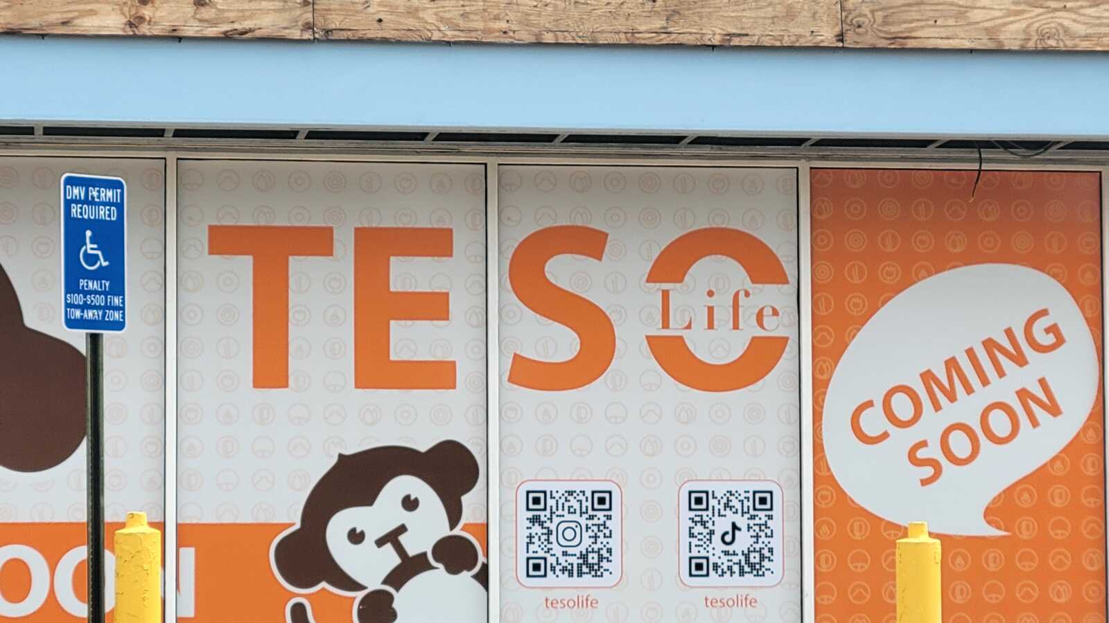 An orange and white sign with bar codes, cartoon monkeys, and the words "Teso Life" and "coming soon."