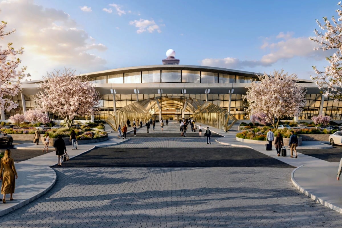 Modern transportation hub with a glass-covered walkway and cherry blossom trees, pedestrians arriving at the entrance.