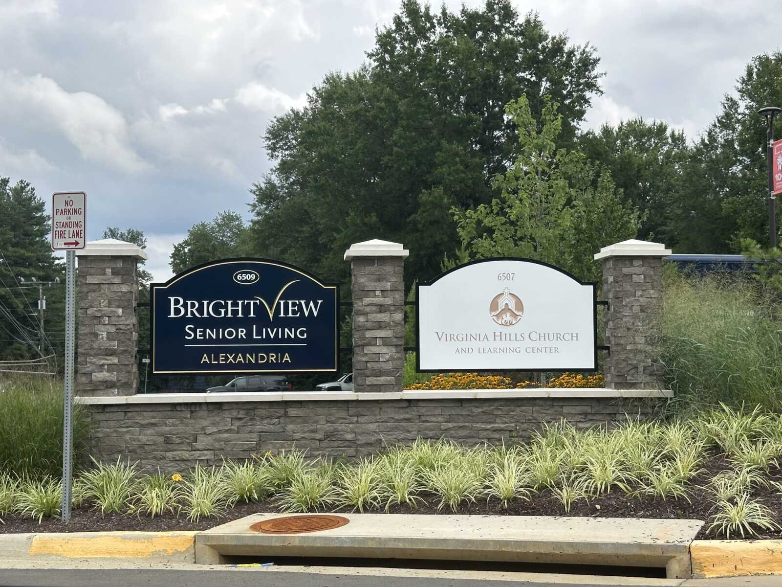 Two signs flanked by stone pillars read BrightView Senior Living Alexandria and Virginia Hills Church and Learning Center, with landscaped plants around.