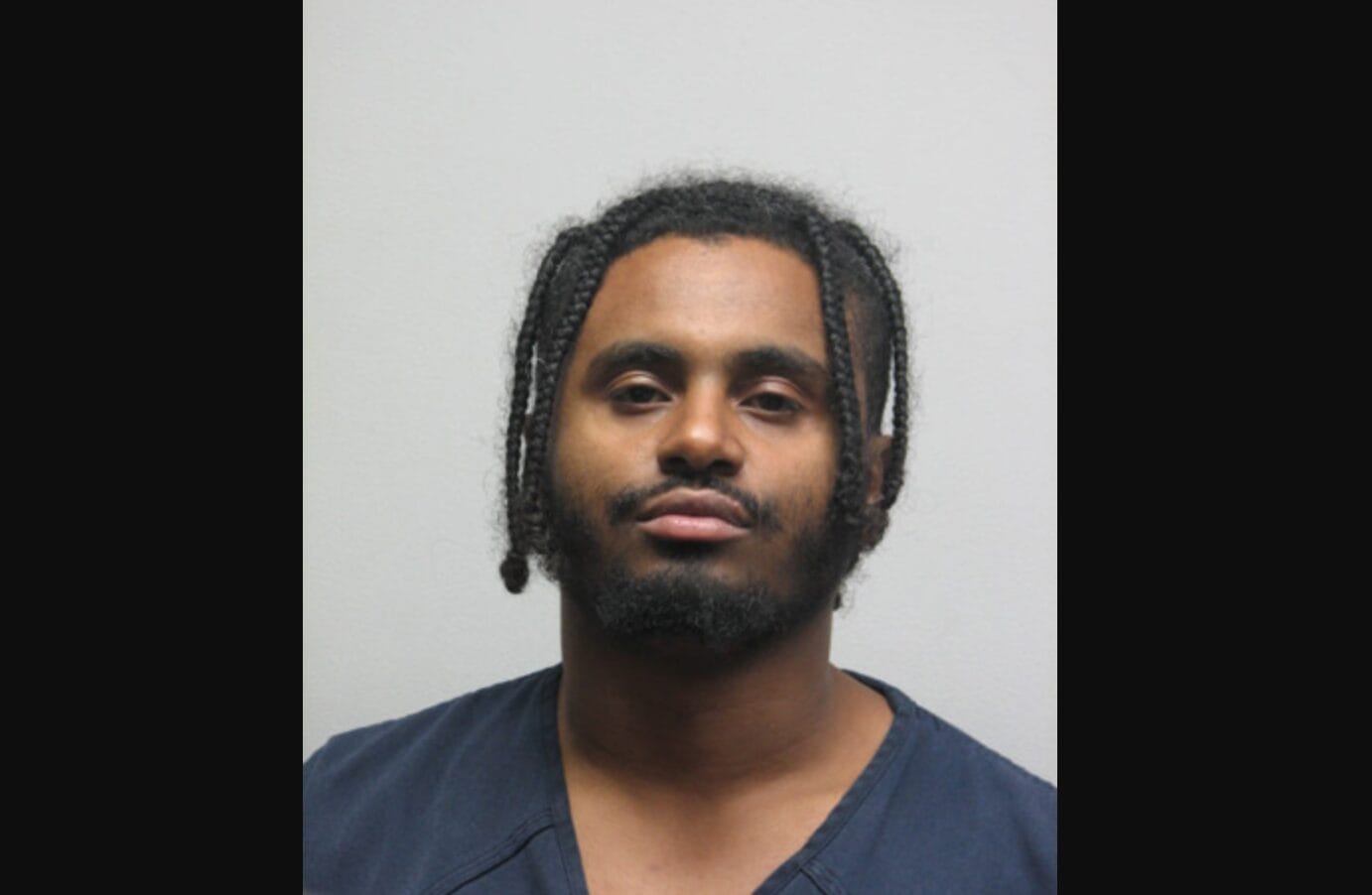 Kumneger Ayalsew (courtesy Fairfax County Police Department) | FFXnow Mugshot-style portrait of a man with braided hair and short beard, wearing a dark blue jumpsuit against a gray background, facing the camera.