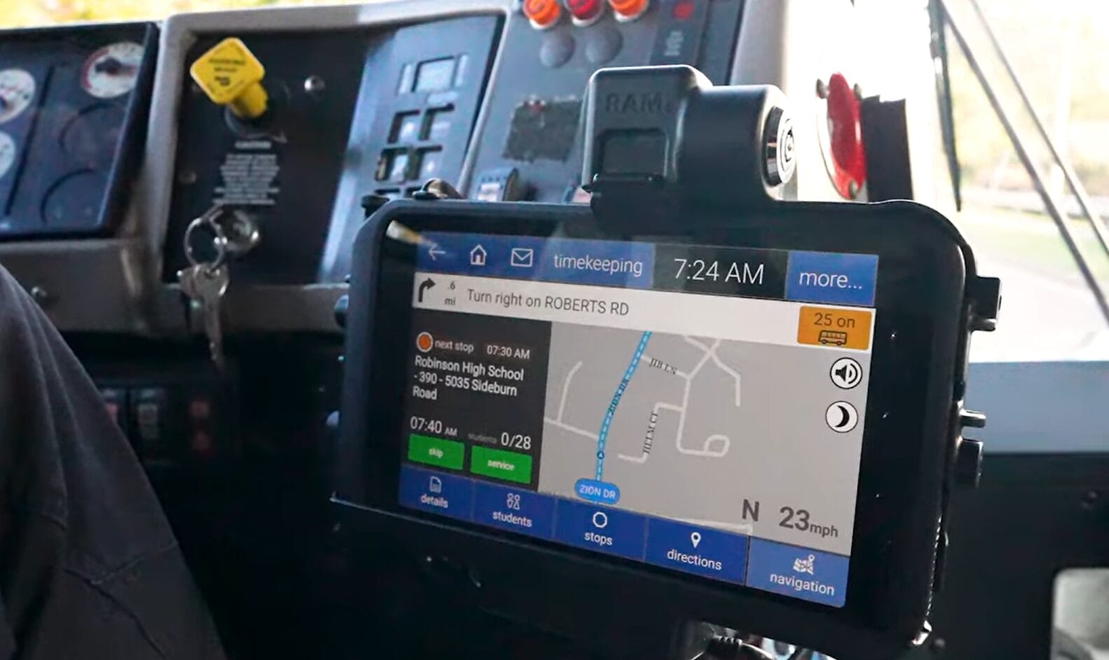 GPS navigation tablet mounted on a bus dashboard showing a street-map and turn-right instruction toward Roberts Rd, time 7:24 AM, with stop details on screen