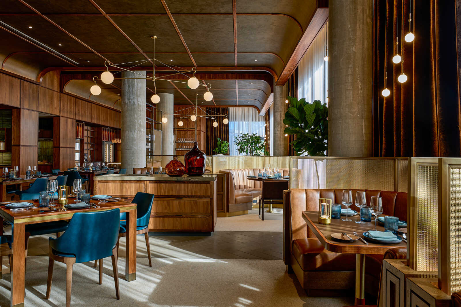 Upscale restaurant interior with wood paneling, blue chairs, and warm globe lighting.