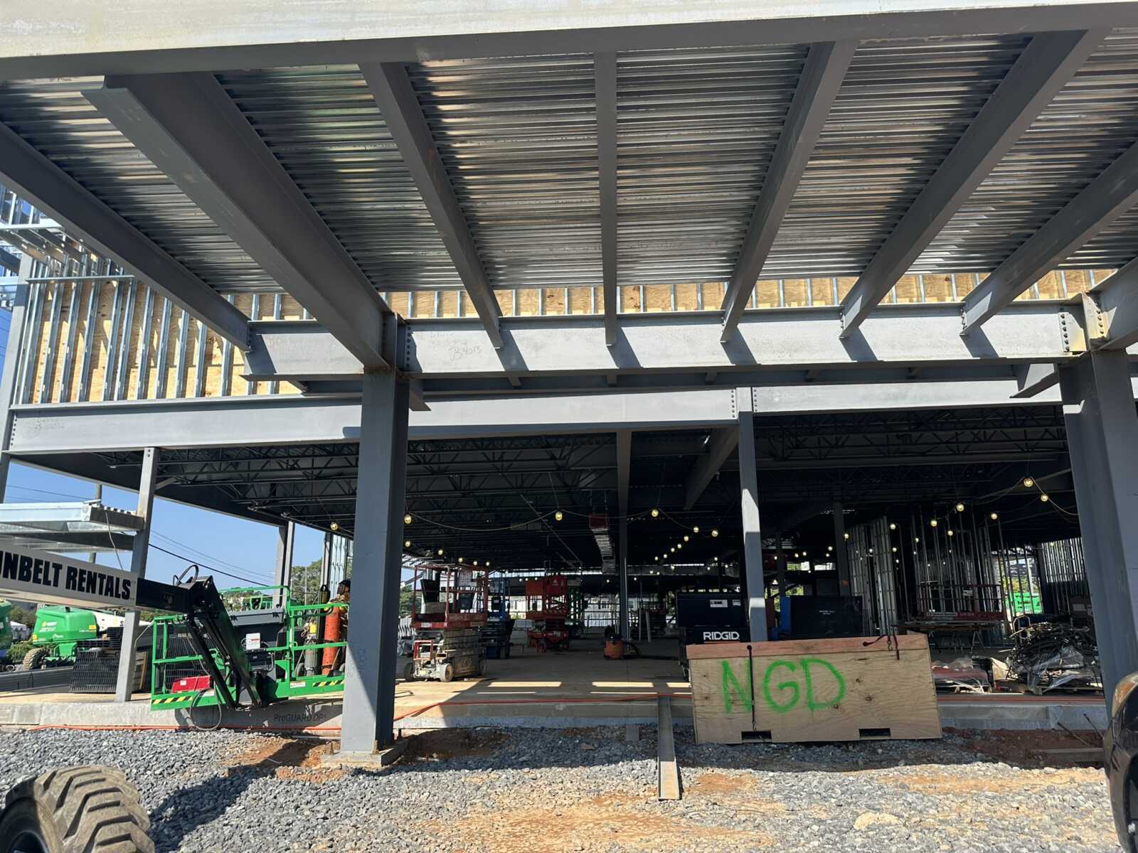 Construction site with steel beams forming a building frame and string lights overhead