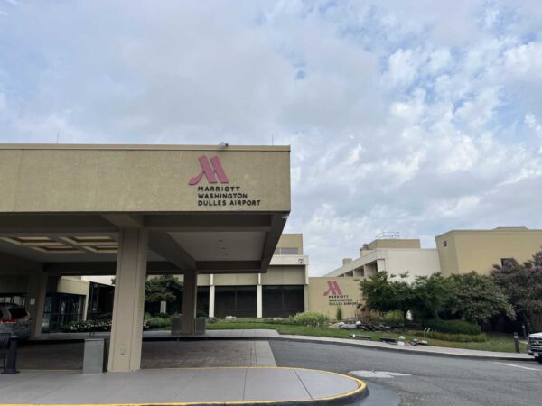 Exterior of Marriott Washington Dulles Airport with pink M logo on beige facade and driveway in foreground.