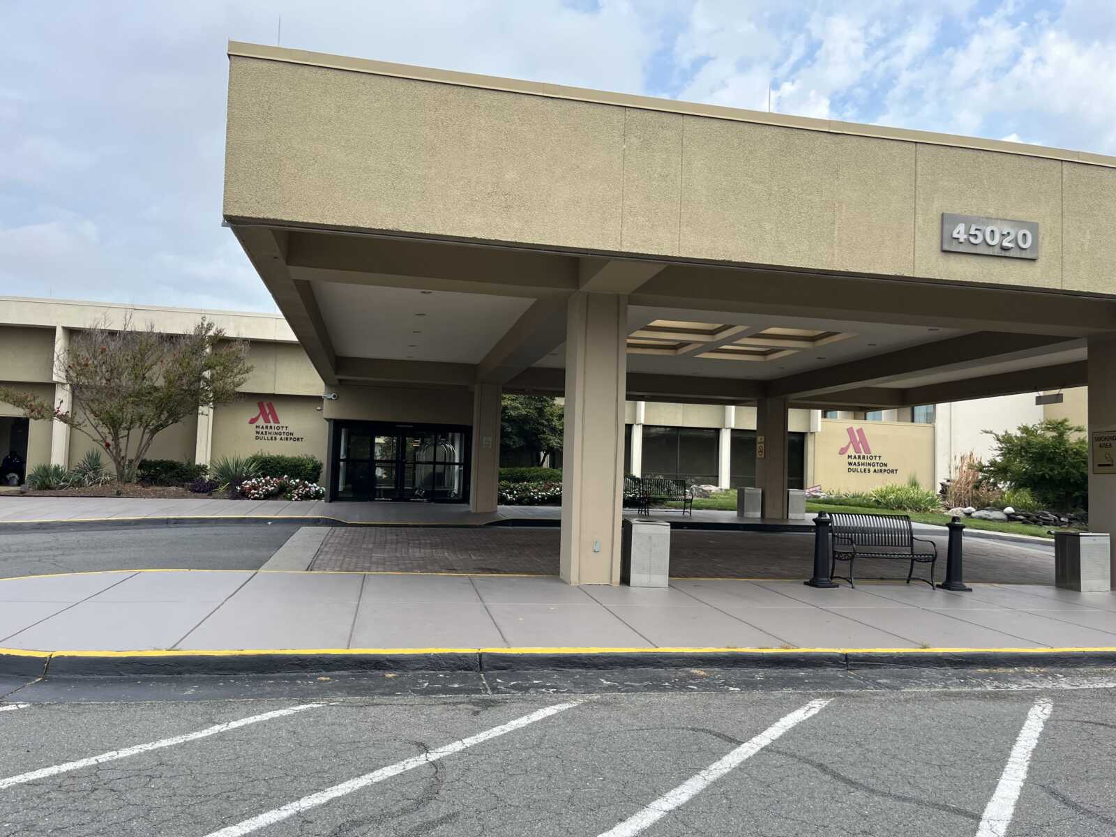 Hotel entrance under a large canopy at Marriott Washington Dulles Airport, with a porte-cochere and a sign showing the hotel name.