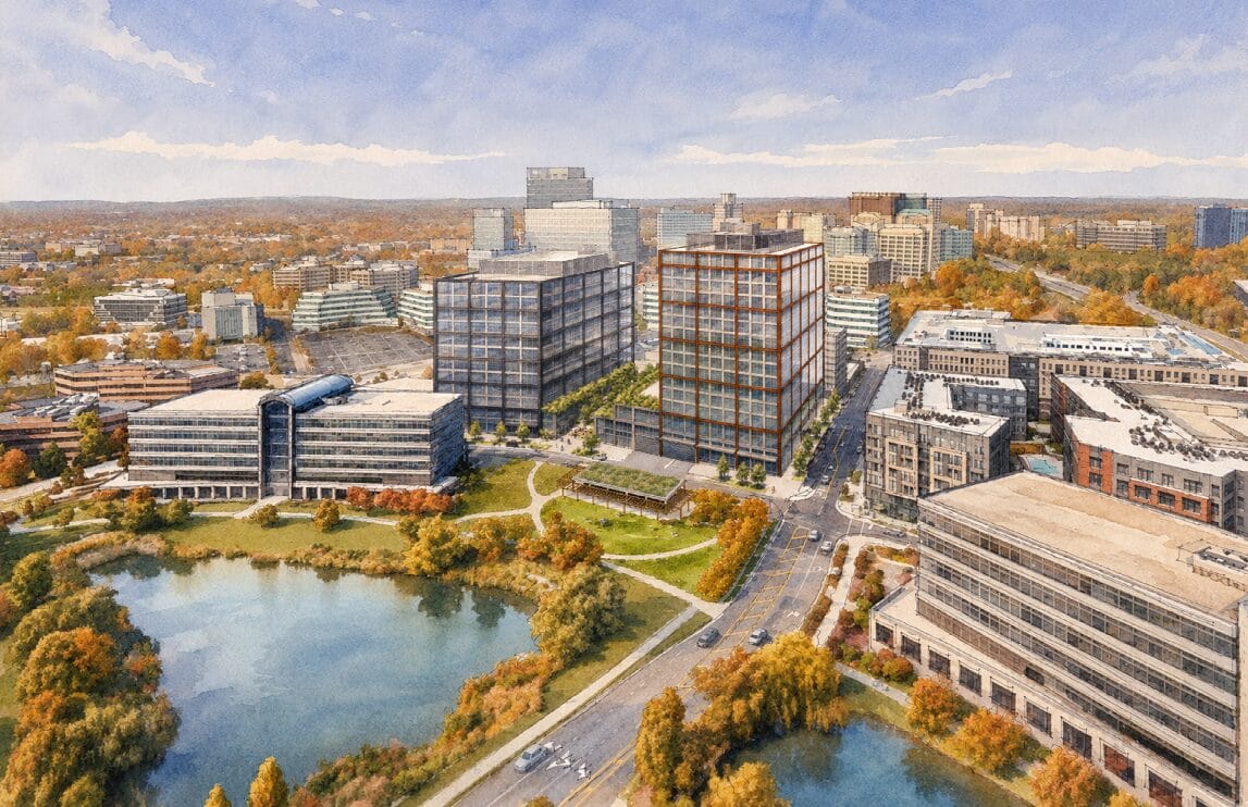 Aerial view of a modern university campus with tall glass buildings, a waterfront lake, and autumn trees.