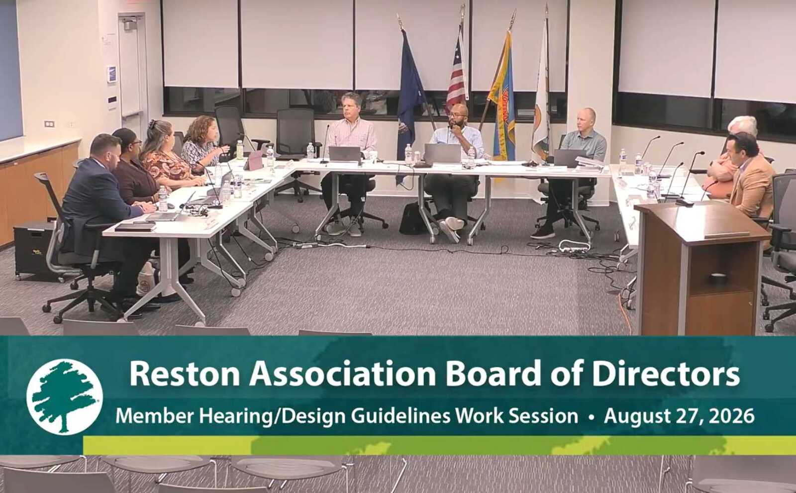 Reston Association Board of Directors discusses concerns about the loss of high school crossing guards at its Aug. 27, 2026 meeting (via RA/YouTube) | FFXnow Reston Association Board of Directors meeting with people seated around a long conference table, flags in the background, and a large banner at the bottom.