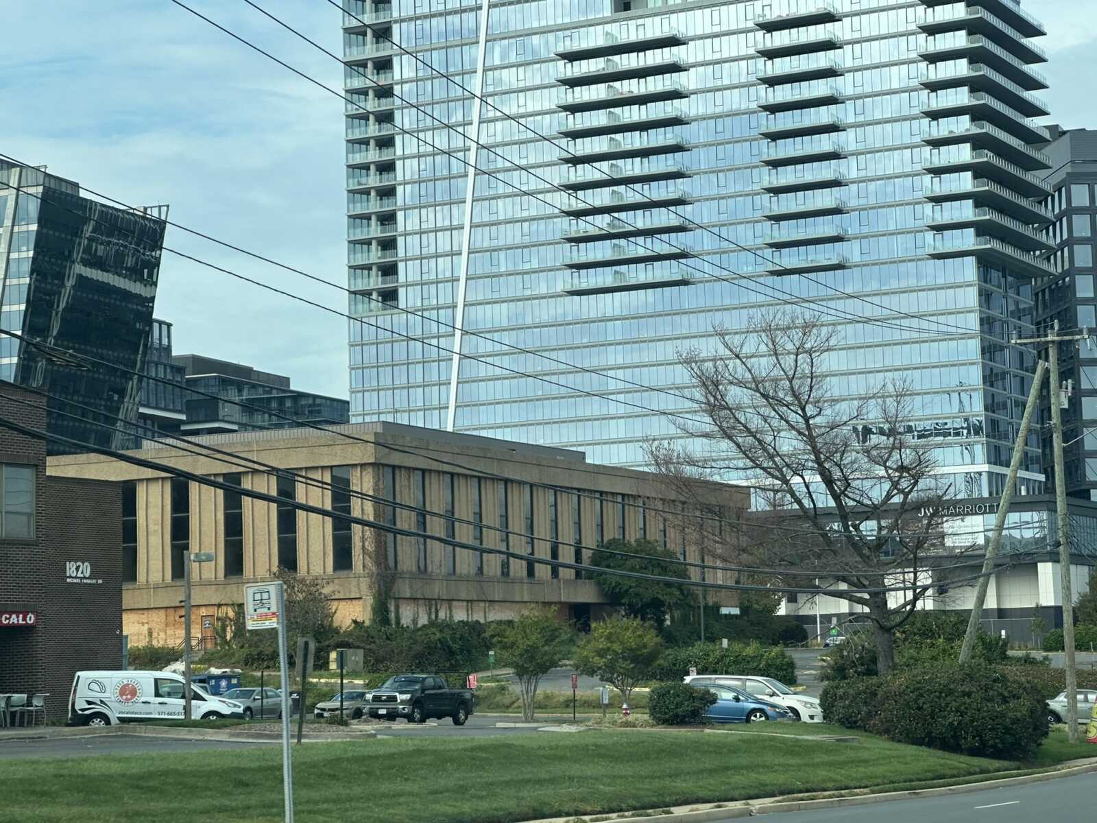 Urban street scene with a tall glass office tower, power lines, and a brick building labeled 1820.