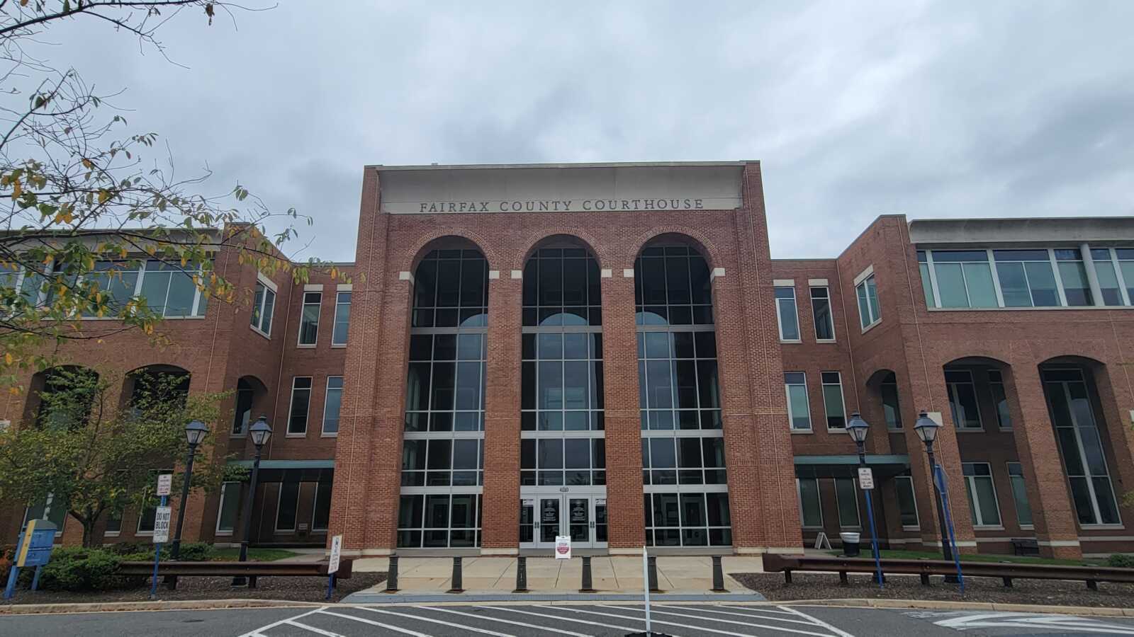 Front view of Fairfax County Courthouse: a brick building with three tall arched windows and a glass-centered entrance.