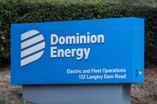 Dominion Energy blue sign with white logo and text, including 'Electric and Fleet Operations' and '132 Langley Dam Road' outdoors.