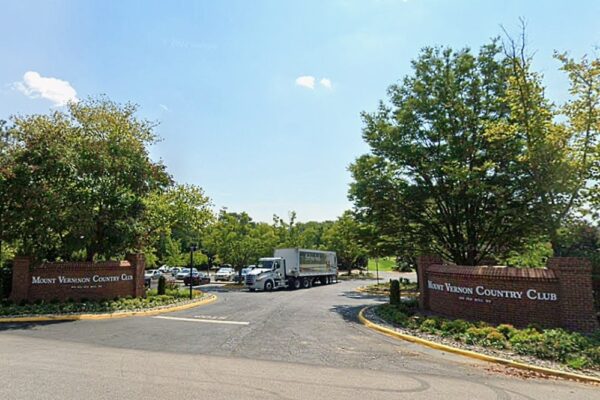 Entrance to Mount Vernon Country Club with brick signs on both sides and a delivery truck turning into the driveway behind landscaped trees
