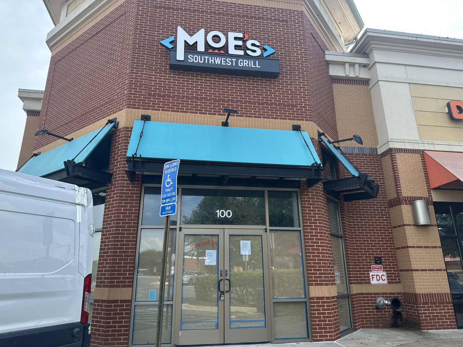 Moe's Southwest Grill storefront with brick exterior, blue awnings, and glass double doors beneath a sign reading MOE'S Southwest Grill.