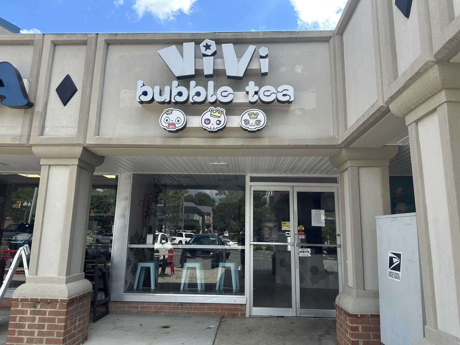Storefront of a bubble tea shop with large white letters 'Vivi' and three cartoon mascot icons above the entrance.