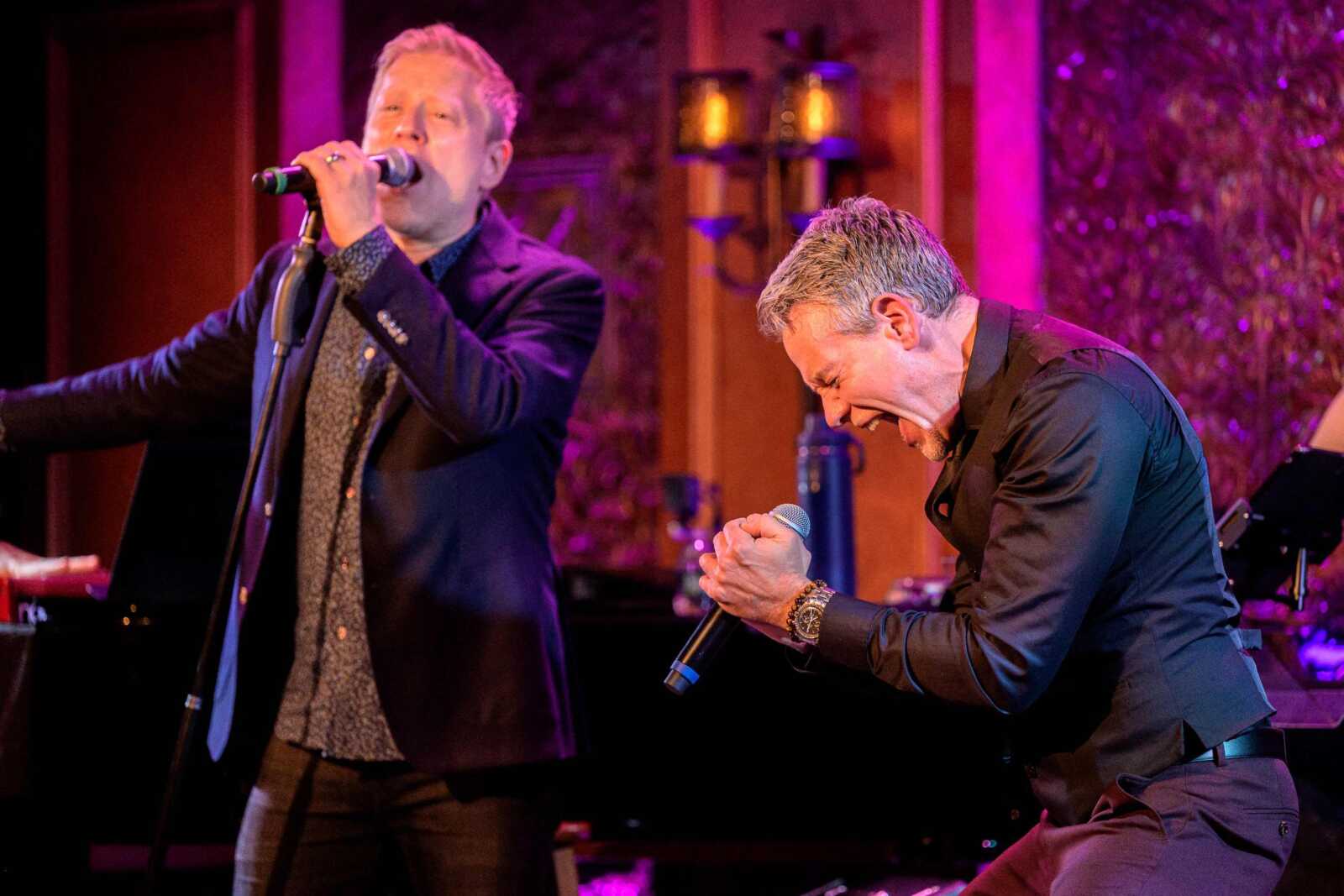Adam Pascal and Anthony Rapp (photo by Adam Kissick for APAP) | FFXnow Two male singers perform on a stage with purple lighting; one sings into a mic while the other leans forward in an energetic moment.