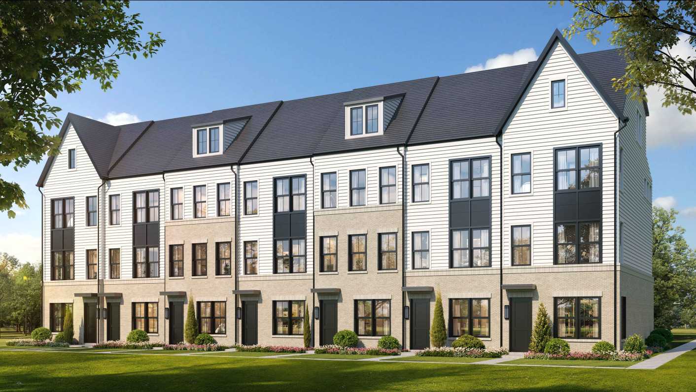 Row of contemporary townhouses with white siding, brick bases, dark roofs, and neatly landscaped front gardens.