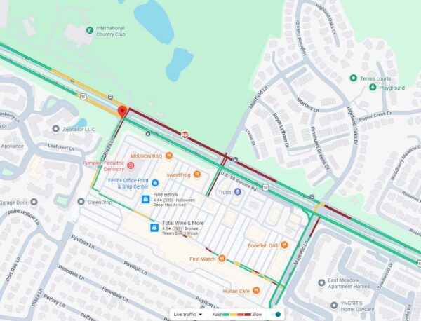 Color-coded road map showing traffic along a highway and nearby streets around a shopping plaza; red=heavy, green=clear traffic