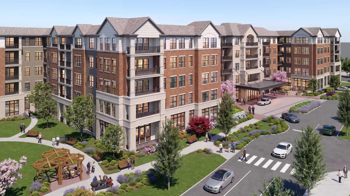 Modern brick apartment complex with green courtyards, a circular gazebo, pedestrians, and cars along a curved street.