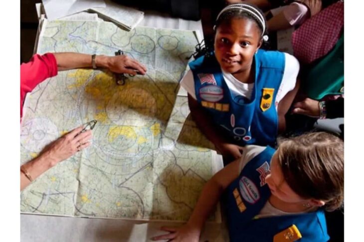 Group around a large map spread on a table, discussing routes and plans.