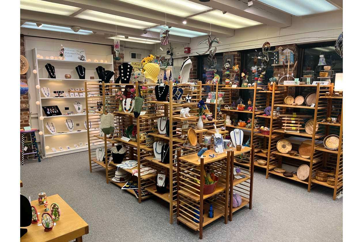 Interior of a craft store with wooden display shelves filled with necklaces, bracelets, and handmade pottery.