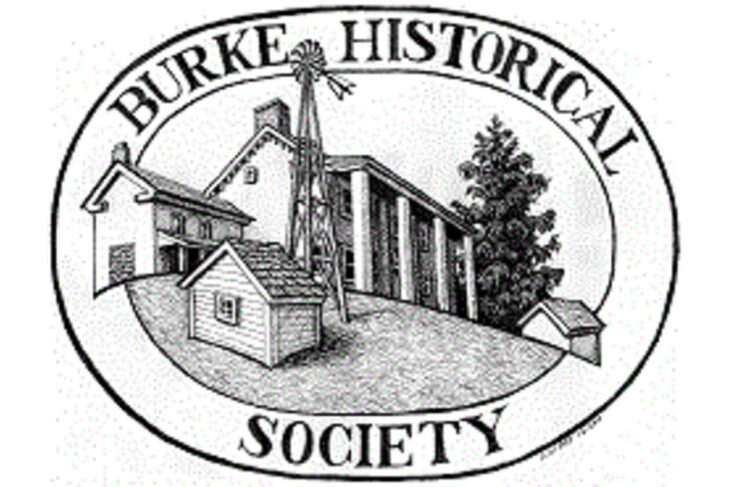 Circular logo for Burke Historical Society showing a cluster of buildings (including a tall windmill-like structure) inside an oval border with the text 'BURKE HISTORICAL SOCIETY'.