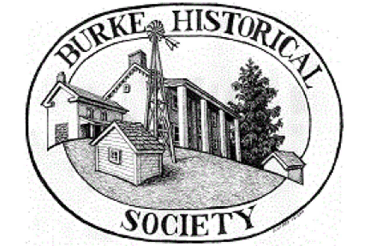 Circular logo for Burke Historical Society showing a cluster of buildings (including a tall windmill-like structure) inside an oval border with the text 'BURKE HISTORICAL SOCIETY'.