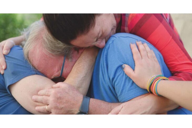 Two people embrace closely in a warm hug, one resting its head on the other's shoulder as a sign of support.