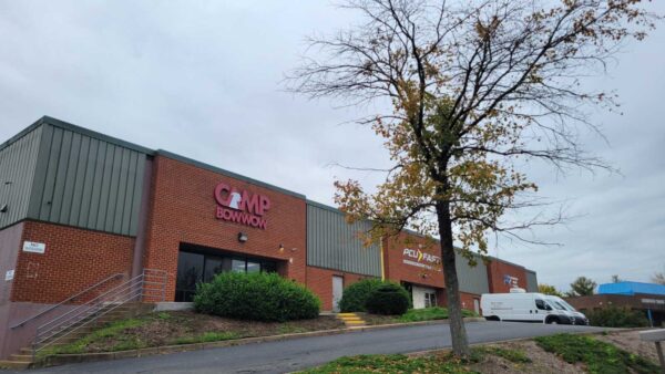 Brick commercial building with CMP BowWow sign, a tree in front, and a white van in the lot under an overcast sky