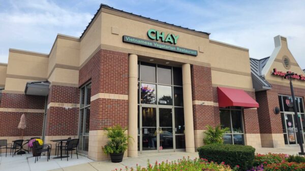 A beige and brick restaurant, framed by small bushes, with the words in green font "Chay Vietnamese Vegetarian Restaurant"