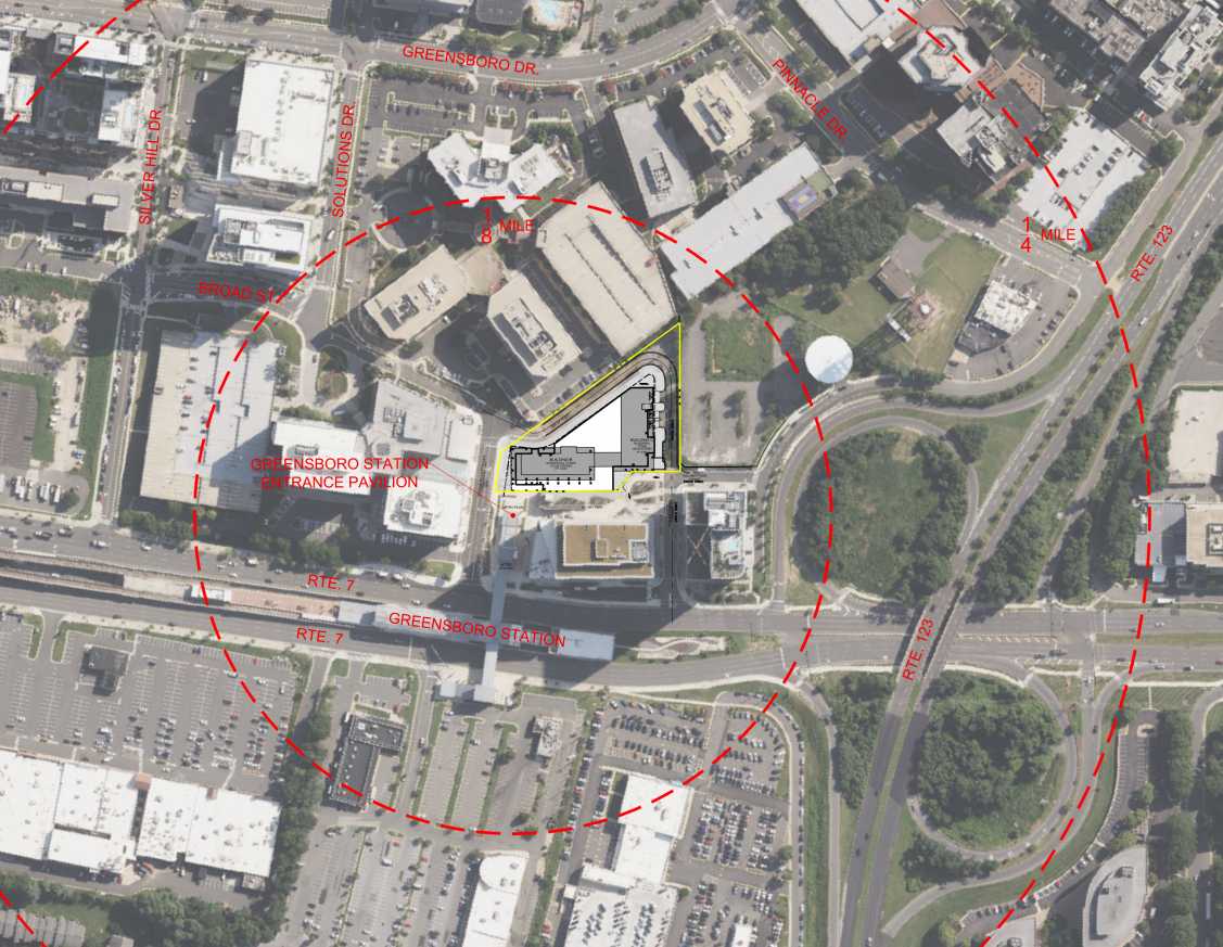 Lincoln Avenue Communities is proposing to develop two all-affordable residential buildings in Tysons Central near the Greensboro Metro station (via VIKA Virginia/Fairfax County) | FFXnow Aerial map of a campus area showing a triangular building outlined in yellow inside a large red dashed circle, with surrounding roads and parking visible to indicate the site.