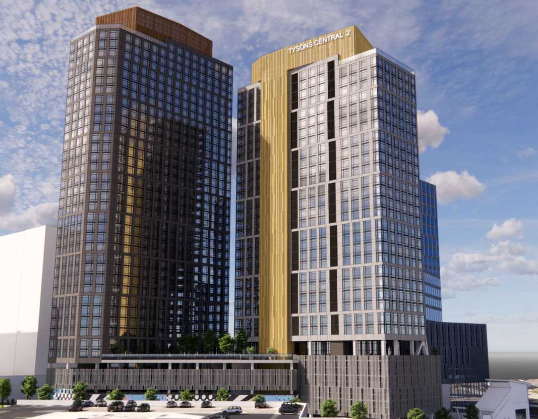 Three-tower glass office complex with a golden central connector labeled Tysons Central II under a blue sky.