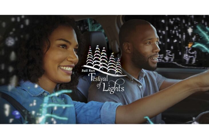 Smiling couple driving in a car with festive lights overlay and the Bull Run Festival of Lights logo.